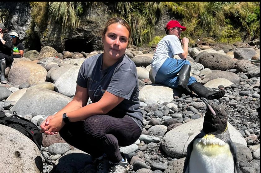 Janine Lavarello - Tristan da Cunha Marine Protection Zone Officer with a penguin on a rocky beach